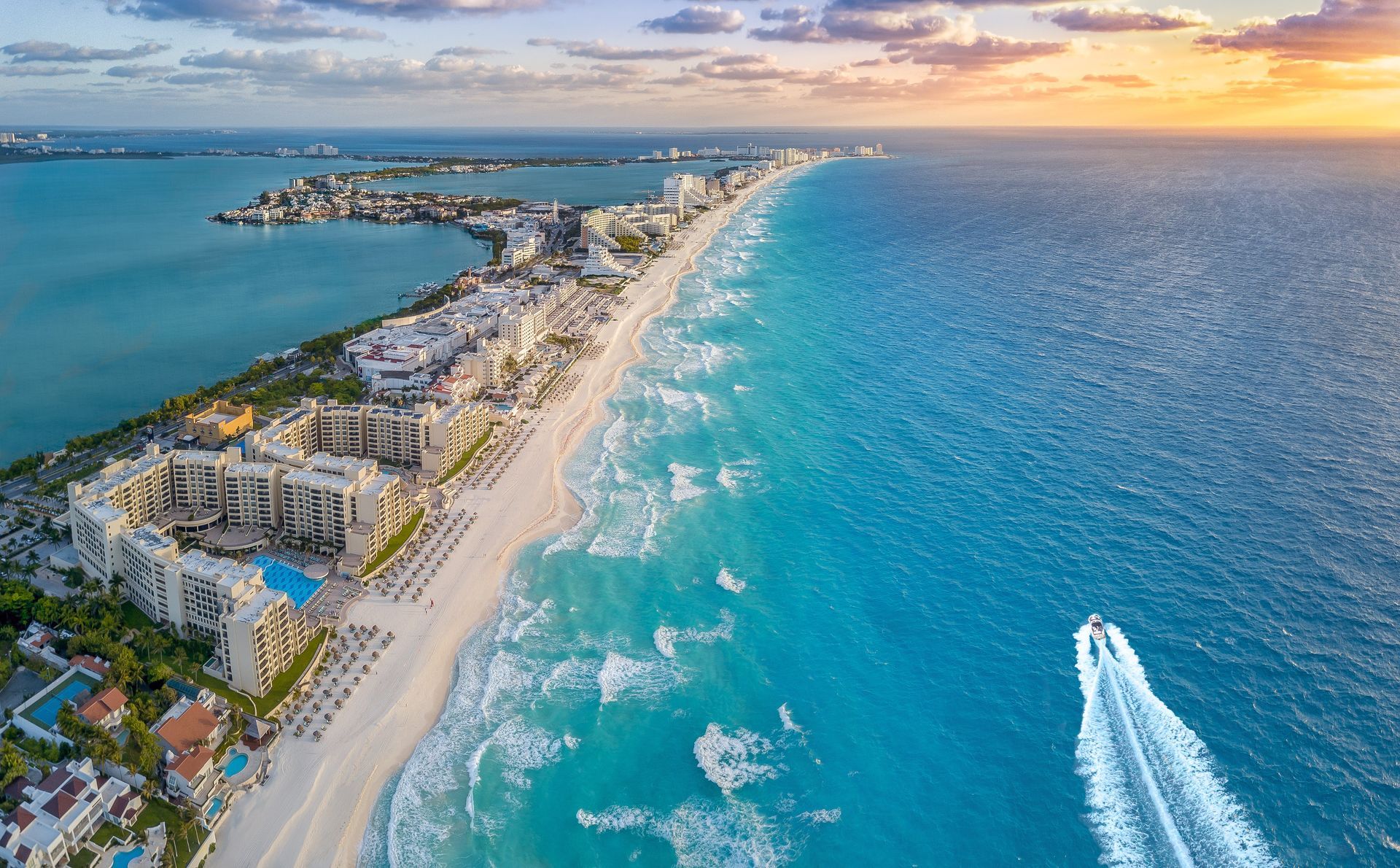 An aerial view of a beach with a boat in the water. Vacation Travel Exclusives