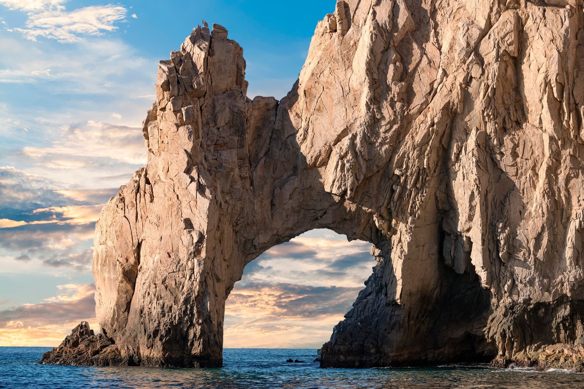 A large rock formation in the middle of the ocean.