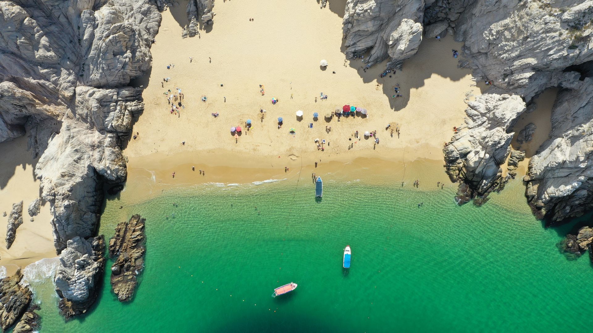 An aerial view of a beach with a boat in the water.