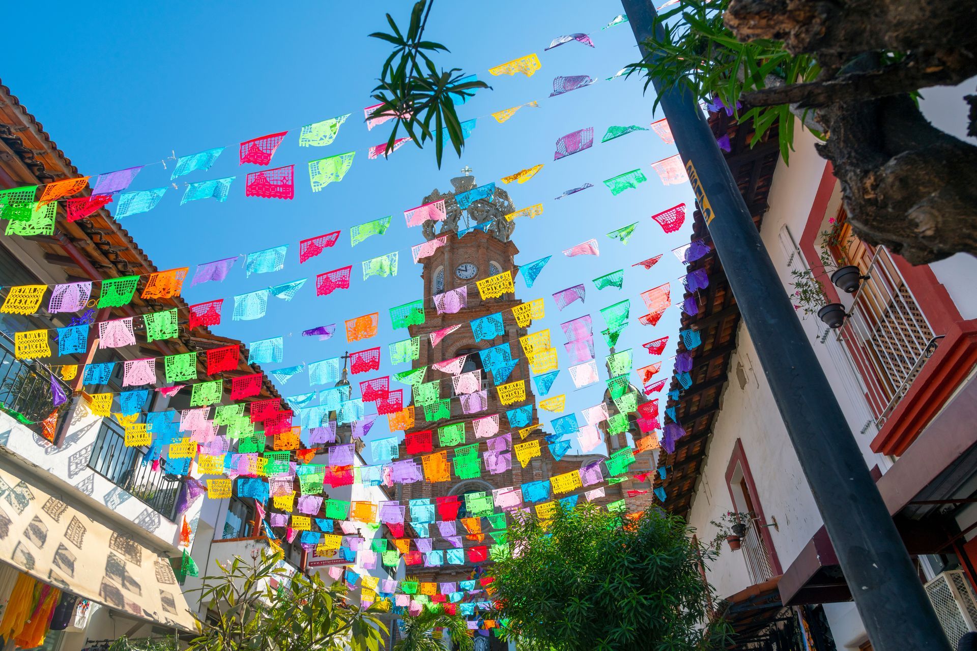 A bunch of colorful flags are hanging from a pole in front of a building.