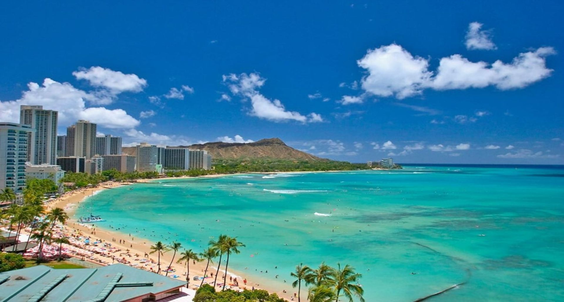 An aerial view of a beach with palm trees and buildings in the background. Vacation Travel Exclusives