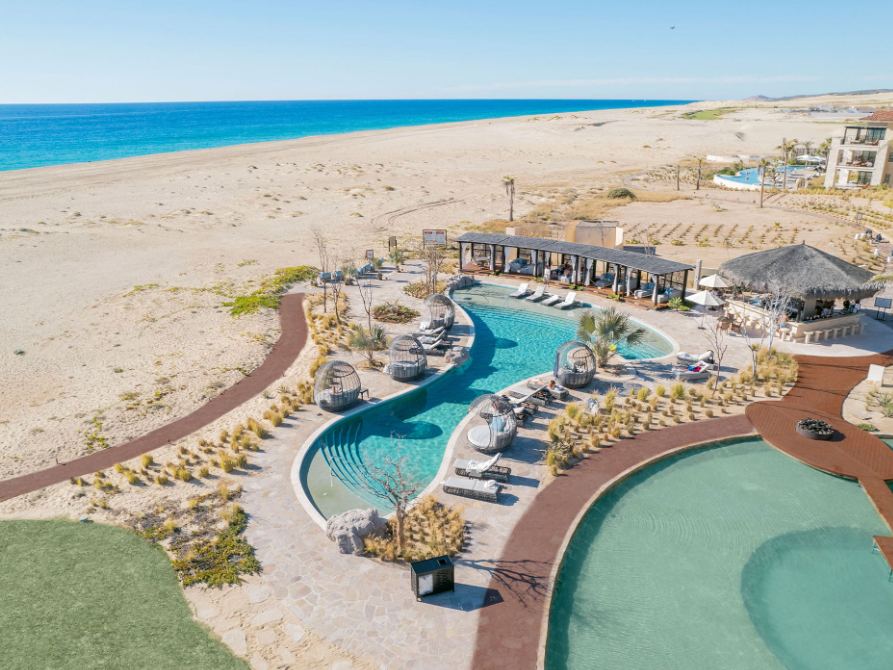 An aerial view of a beach at Pacific Dunes with a large swimming pool. Vacation Travel Exclusives