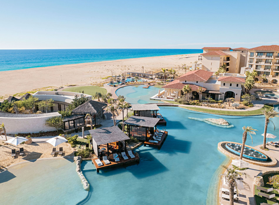 An aerial view of Pacific Dunes with a large pool and a beach in the background. Vacation Travel Exclusives
