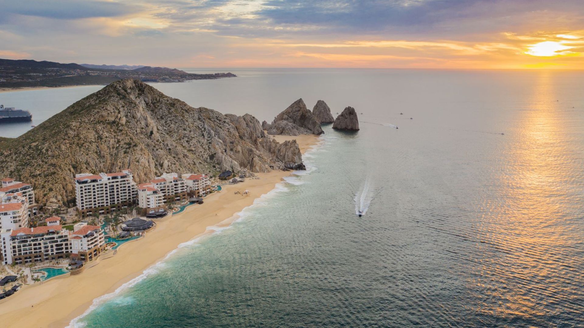 An aerial view of a beach and the ocean at sunset.