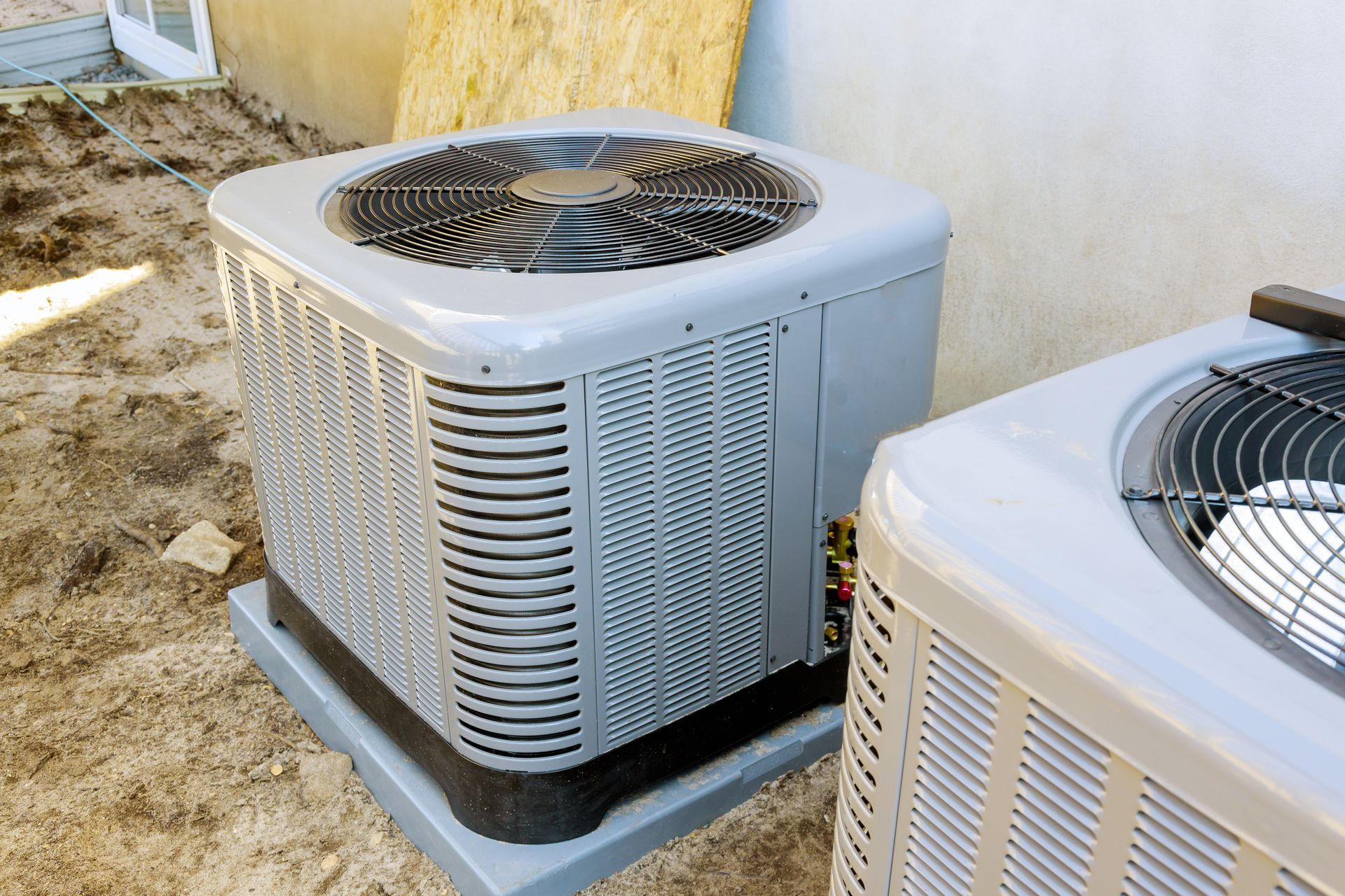Outdoor air conditioning units installed on a concrete pad beside a residential building.