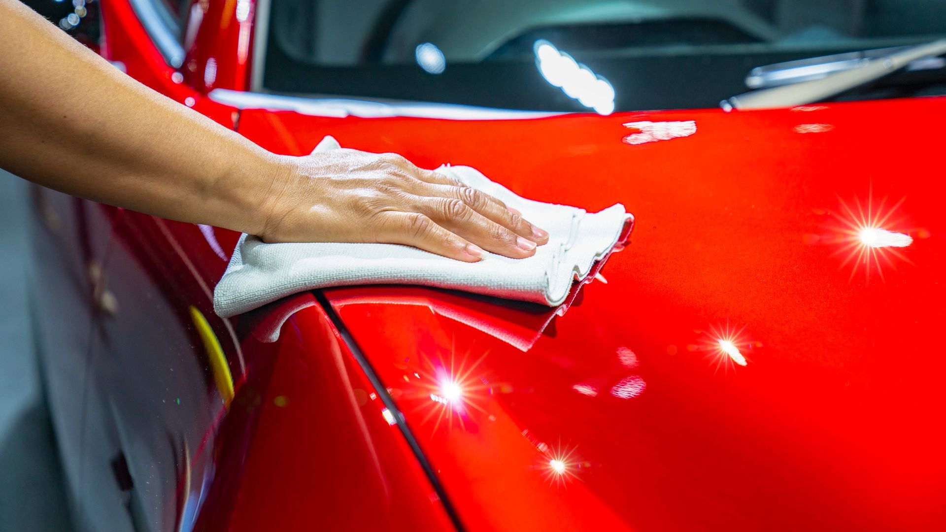 A person is cleaning a red car with a towel - Eustis, FL - Bay Street Paint and Body