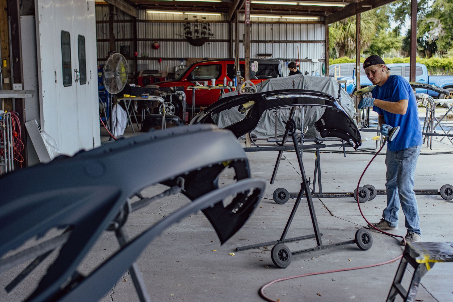 A man is working on the engine of a car in a garage - Eustis, FL - Bay Street Paint and Body