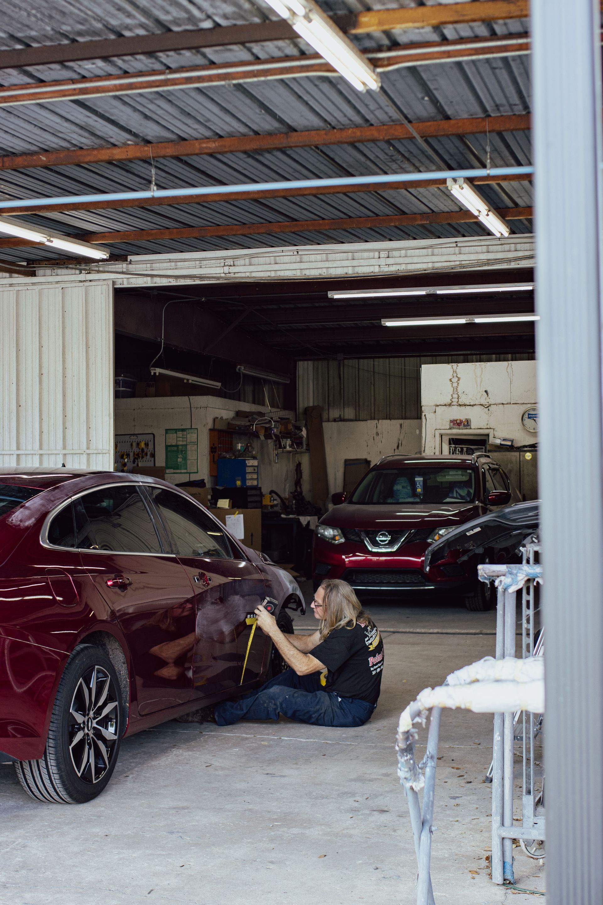 A person is cleaning a red car with a towel - Eustis, FL - Bay Street Paint and Body