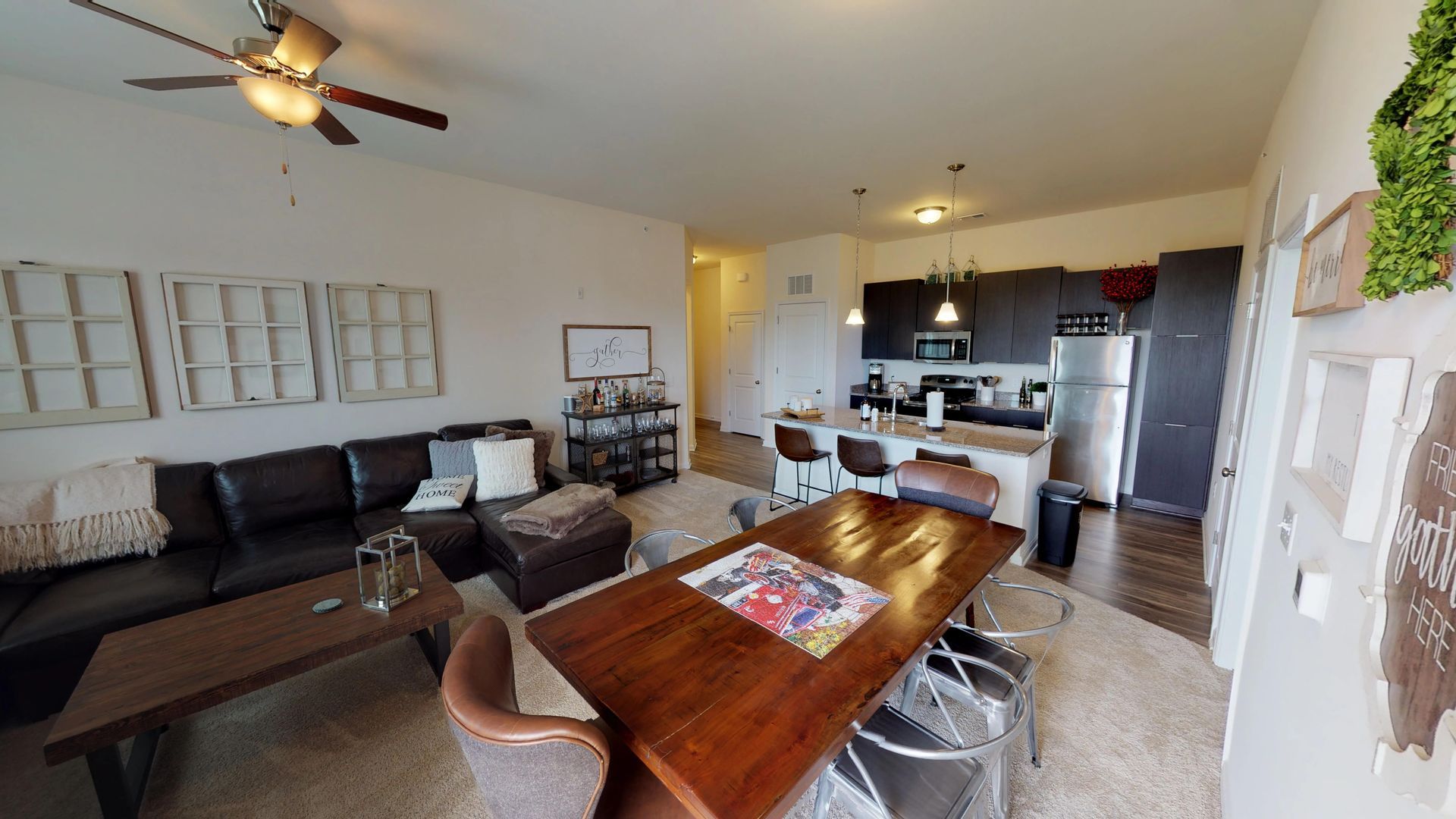 A living room with a dining table and a ceiling fan