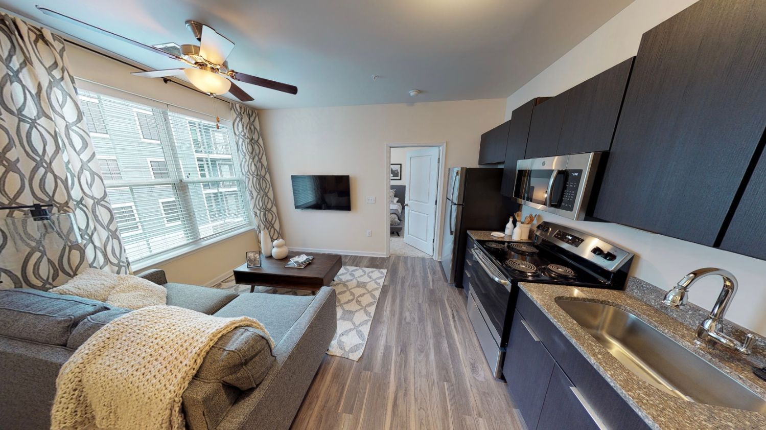A living room and kitchen in a house with a ceiling fan.