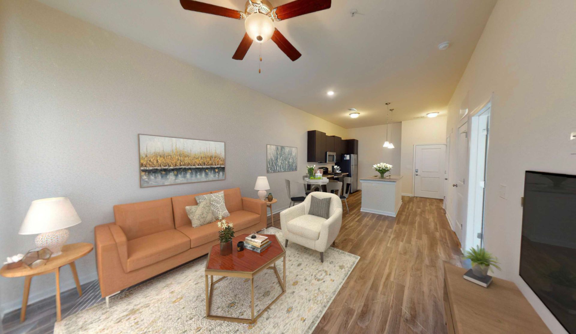 A living room with a couch , chair , coffee table and ceiling fan.
