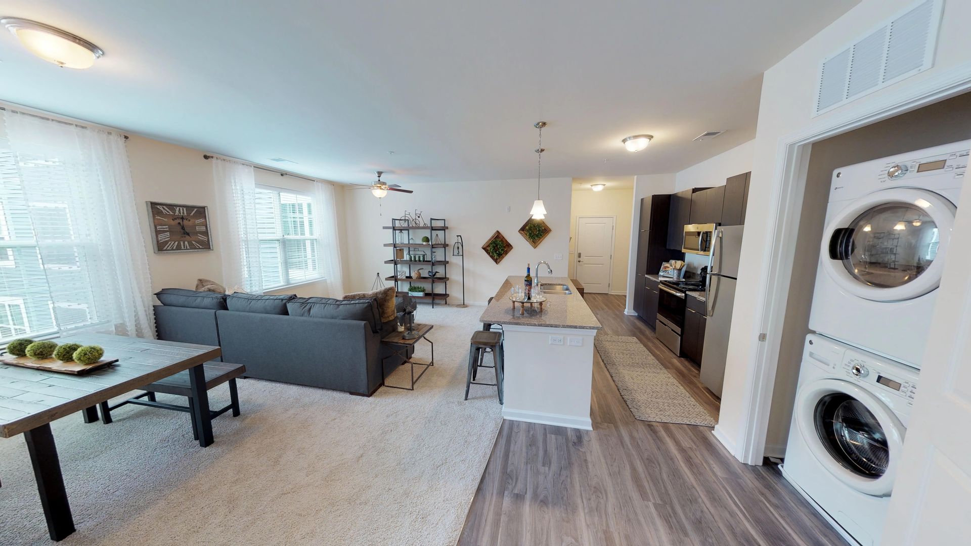 A living room with a washer and dryer stacked on top of each other.