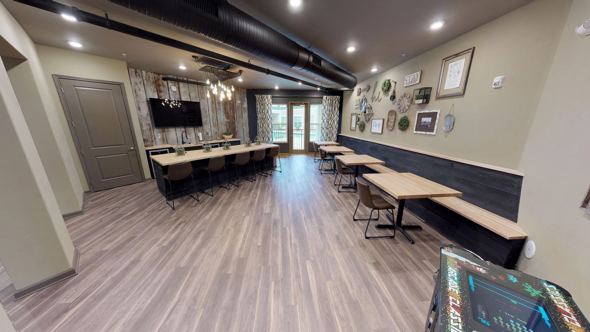 A large room with tables and chairs and a television on the wall.