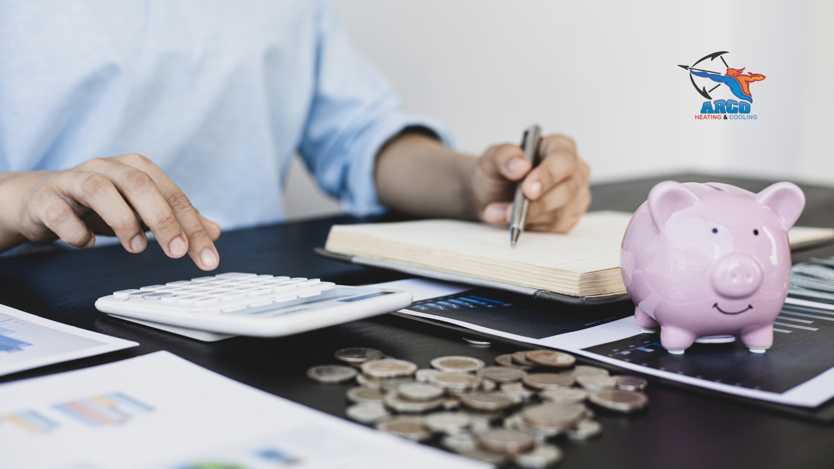 A person is sitting at a table with a piggy bank and a calculator.