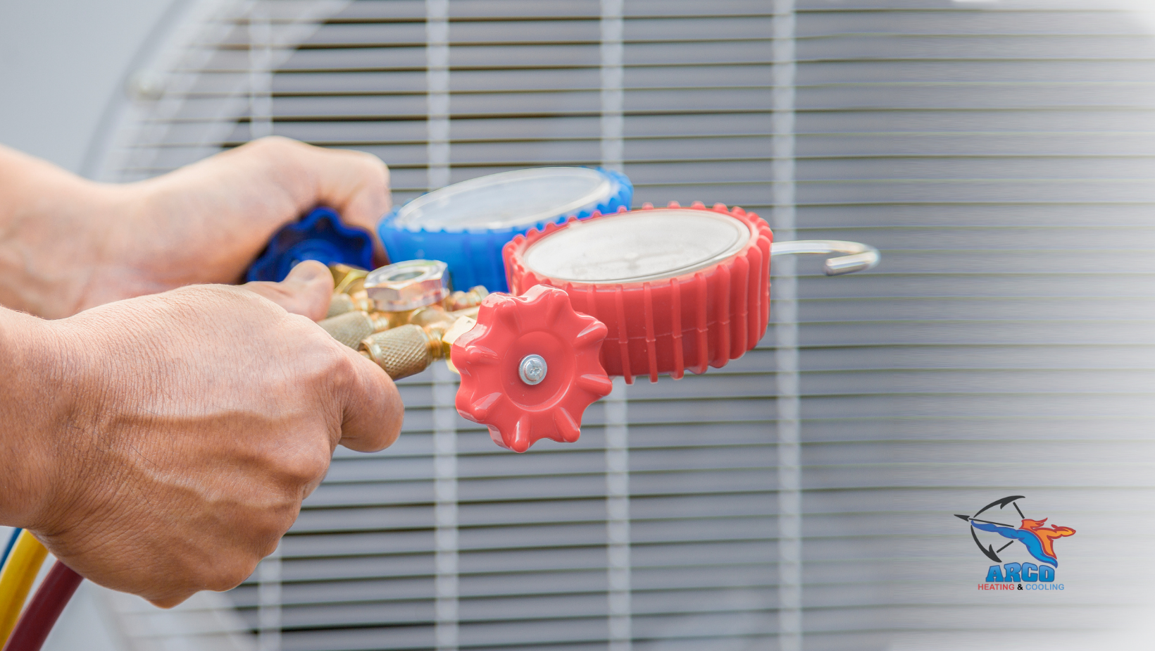 A person is working on an air conditioner with a hose and gauges.