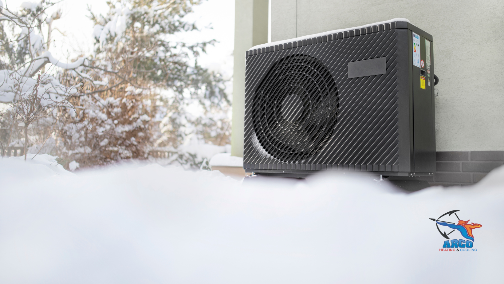 A black air conditioner is sitting in the snow next to a window.