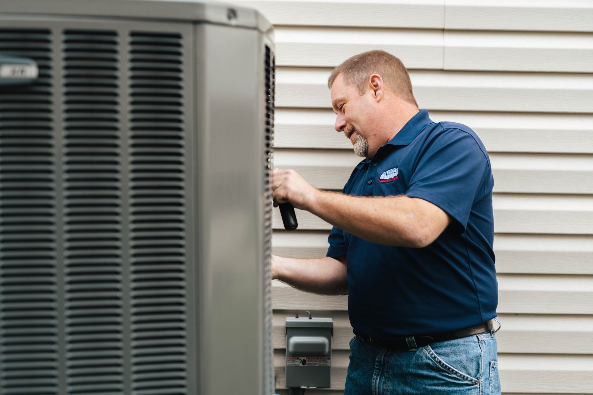 a man diagnosing an outside HVAC unit