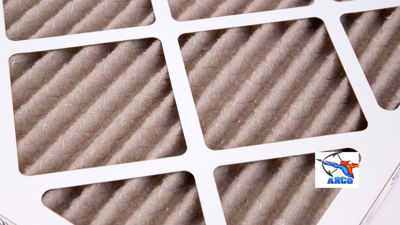Close-up of a white window air filter with gray dust and diagonal pleats