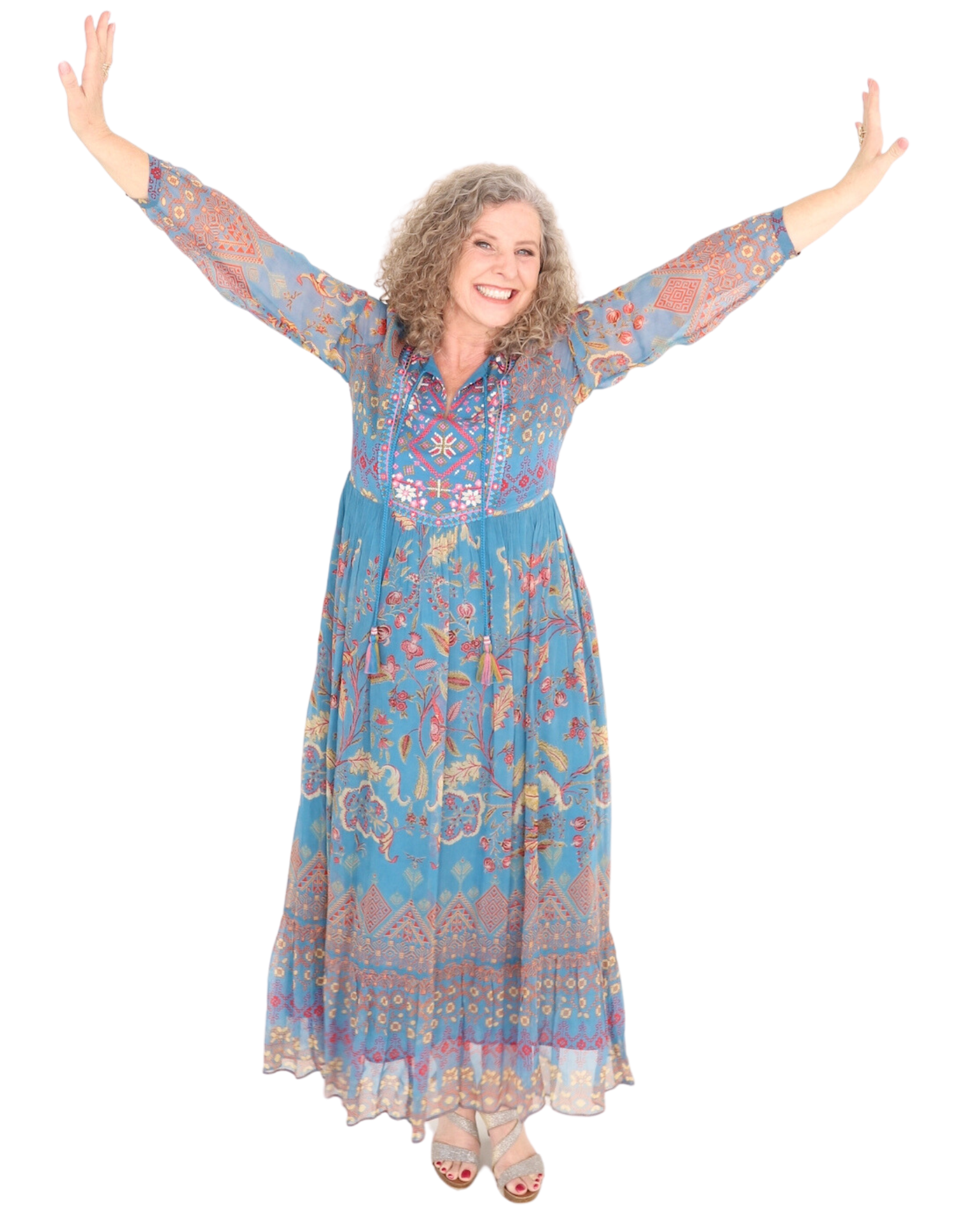Woman in blue patterned dress with arms raised, smiling.