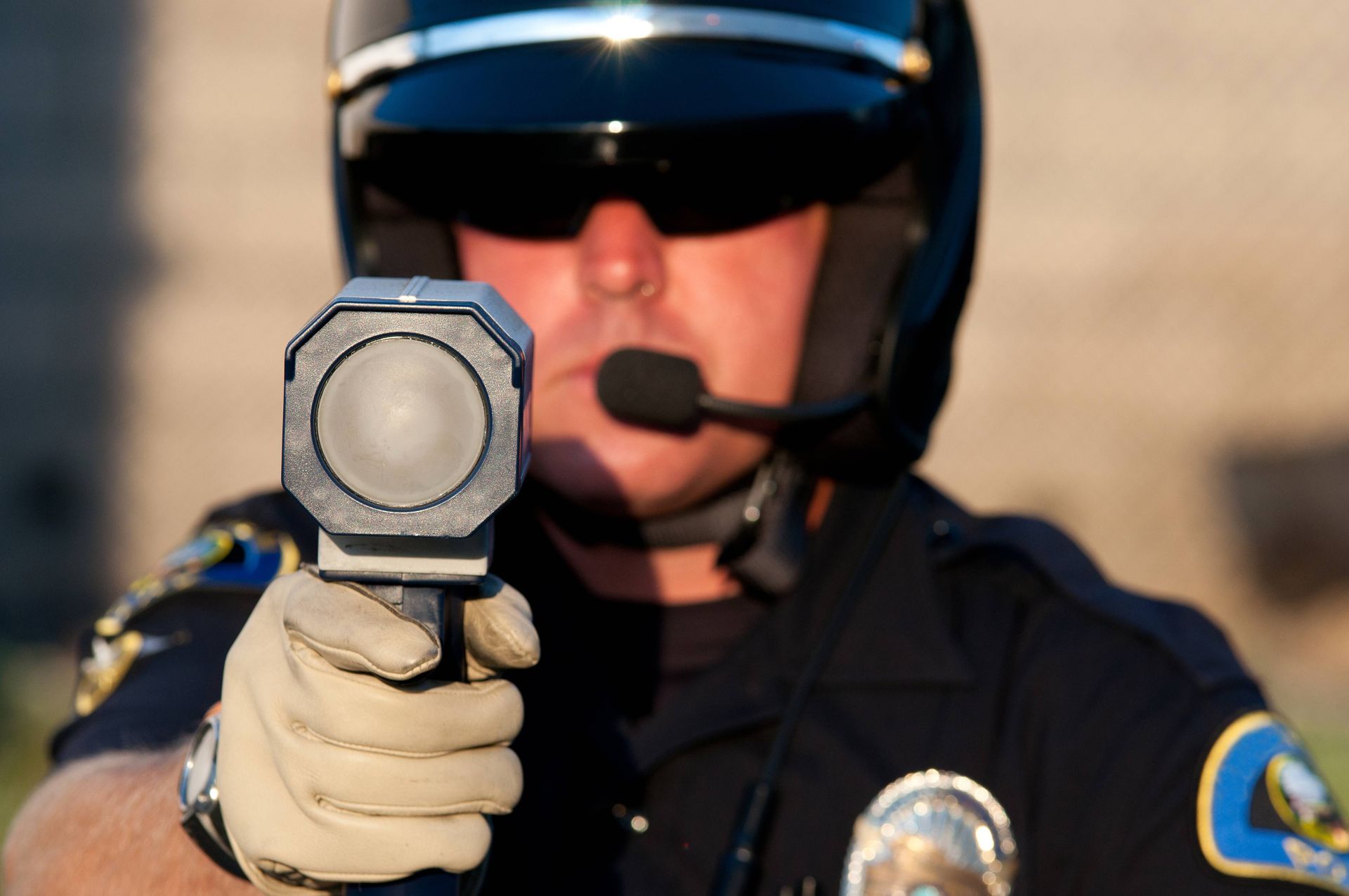 Police officer in uniform pointing a speed radar gun.