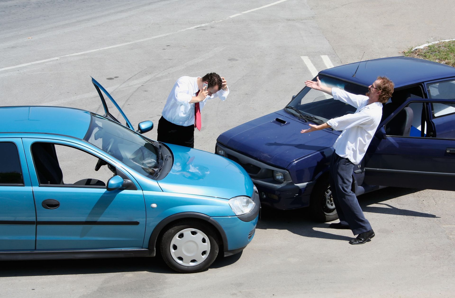 Two cars crashed; two men reacting. One distraught, other gesturing. Sunny day, outdoor setting.