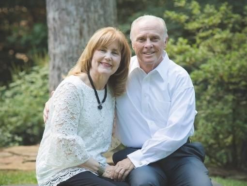 Dr. Mark and Allison Rutland sitting outdoors, embracing. The woman wears a white lace top, the man a white shirt.