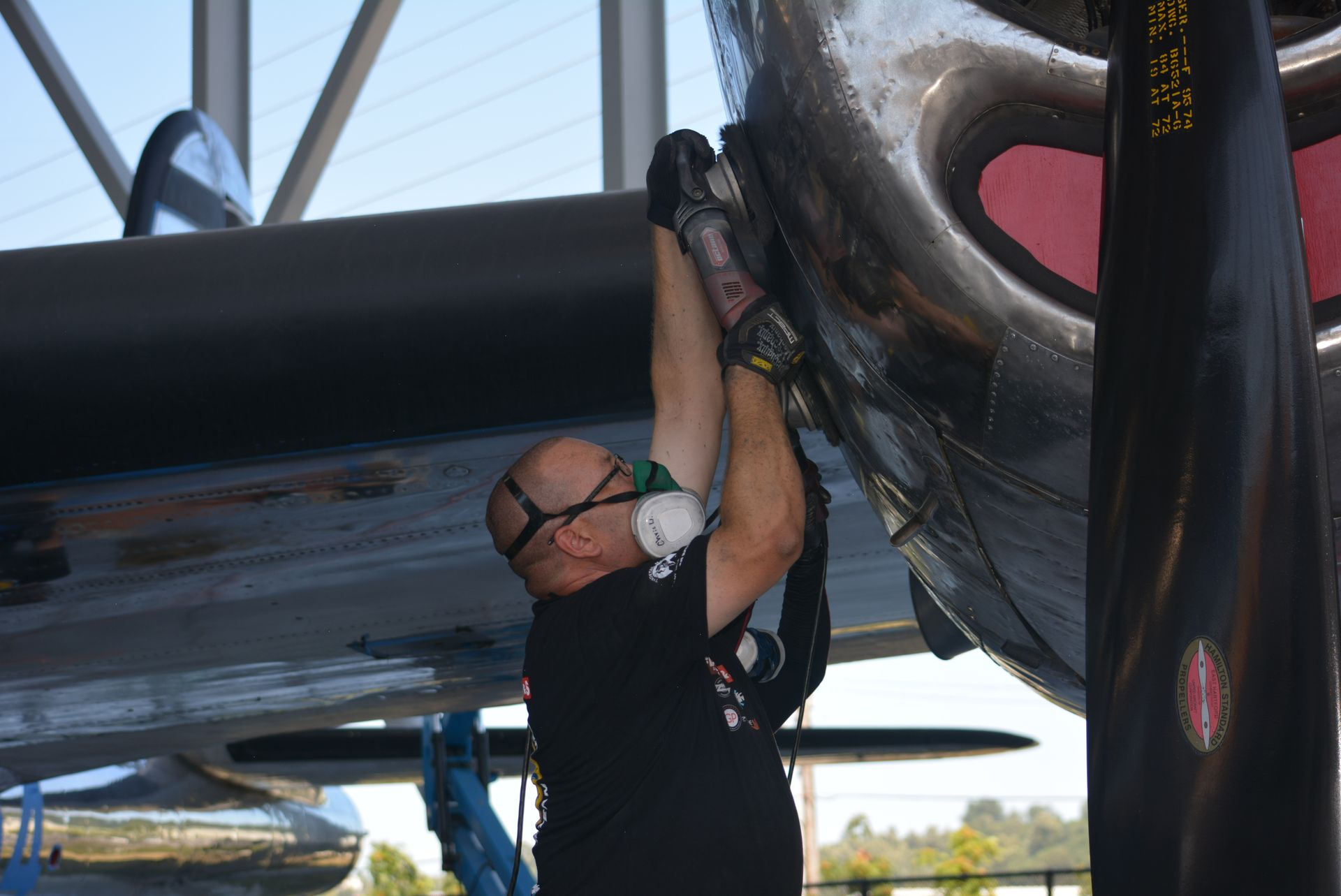 A man wearing a mask is working on a plane