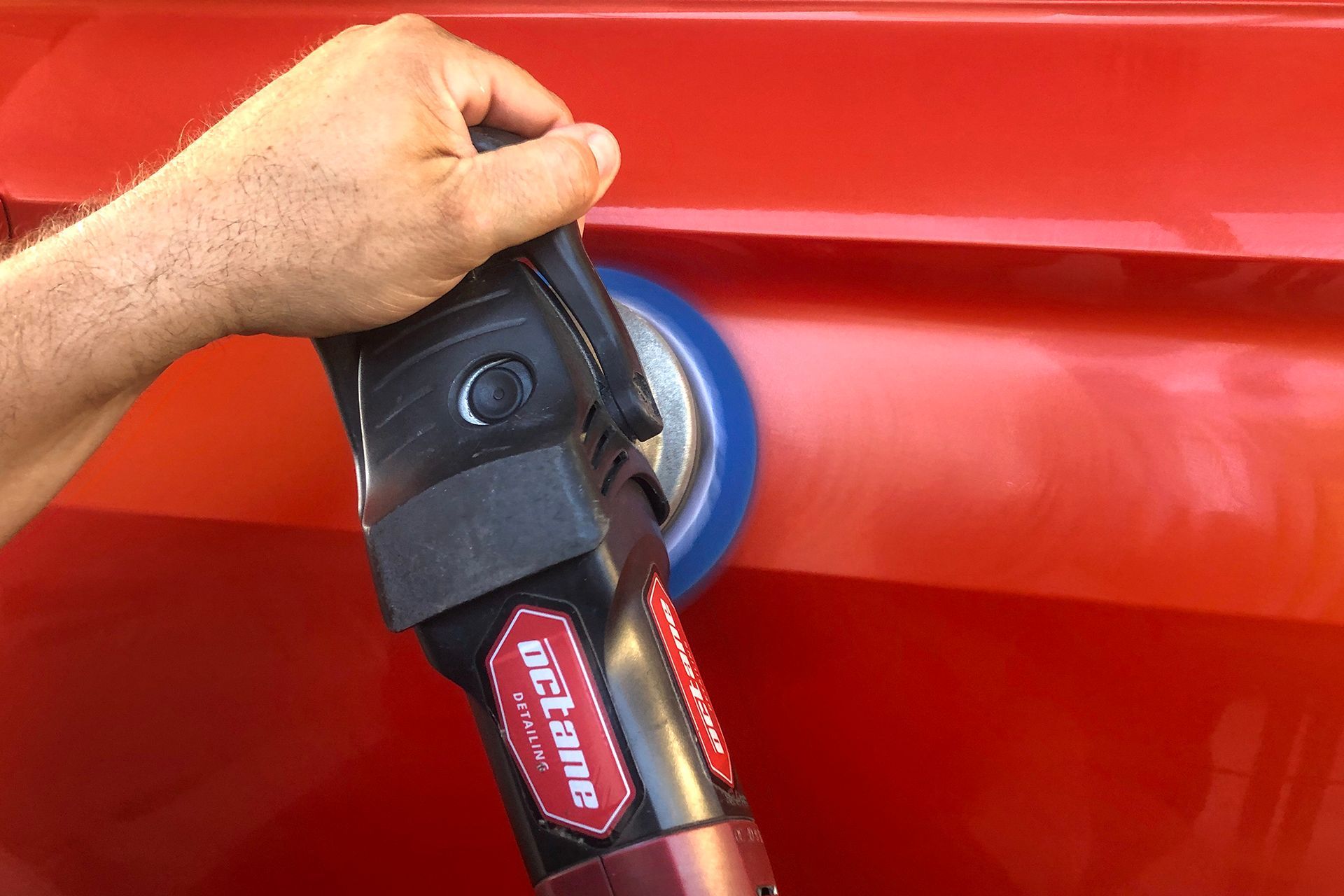 A man is polishing a car with a machine.