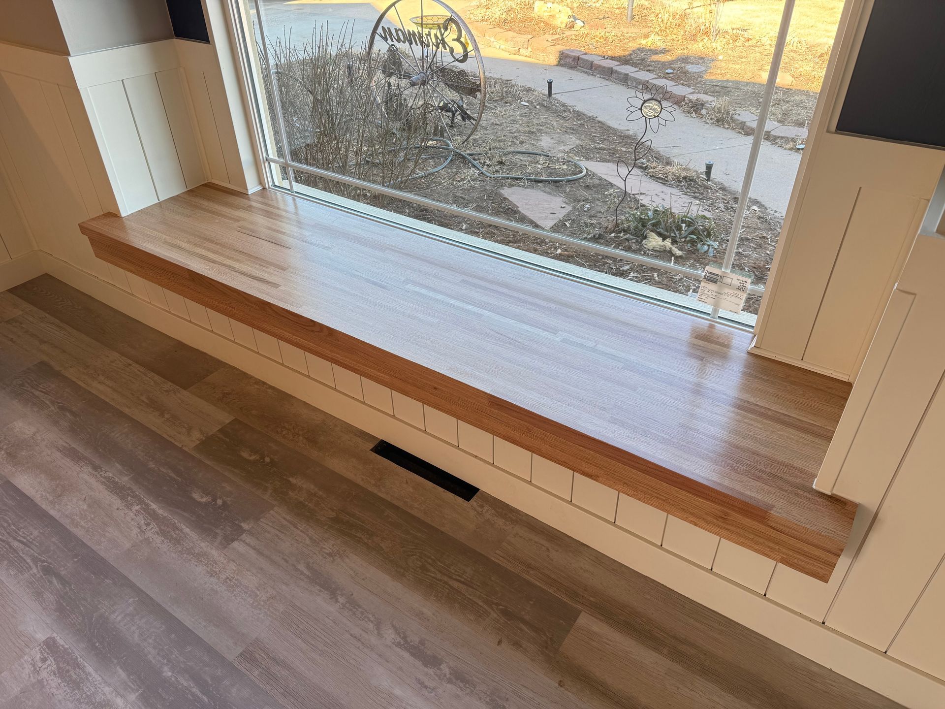 Wooden window sill inside a room, overlooking a sunny outdoor view.