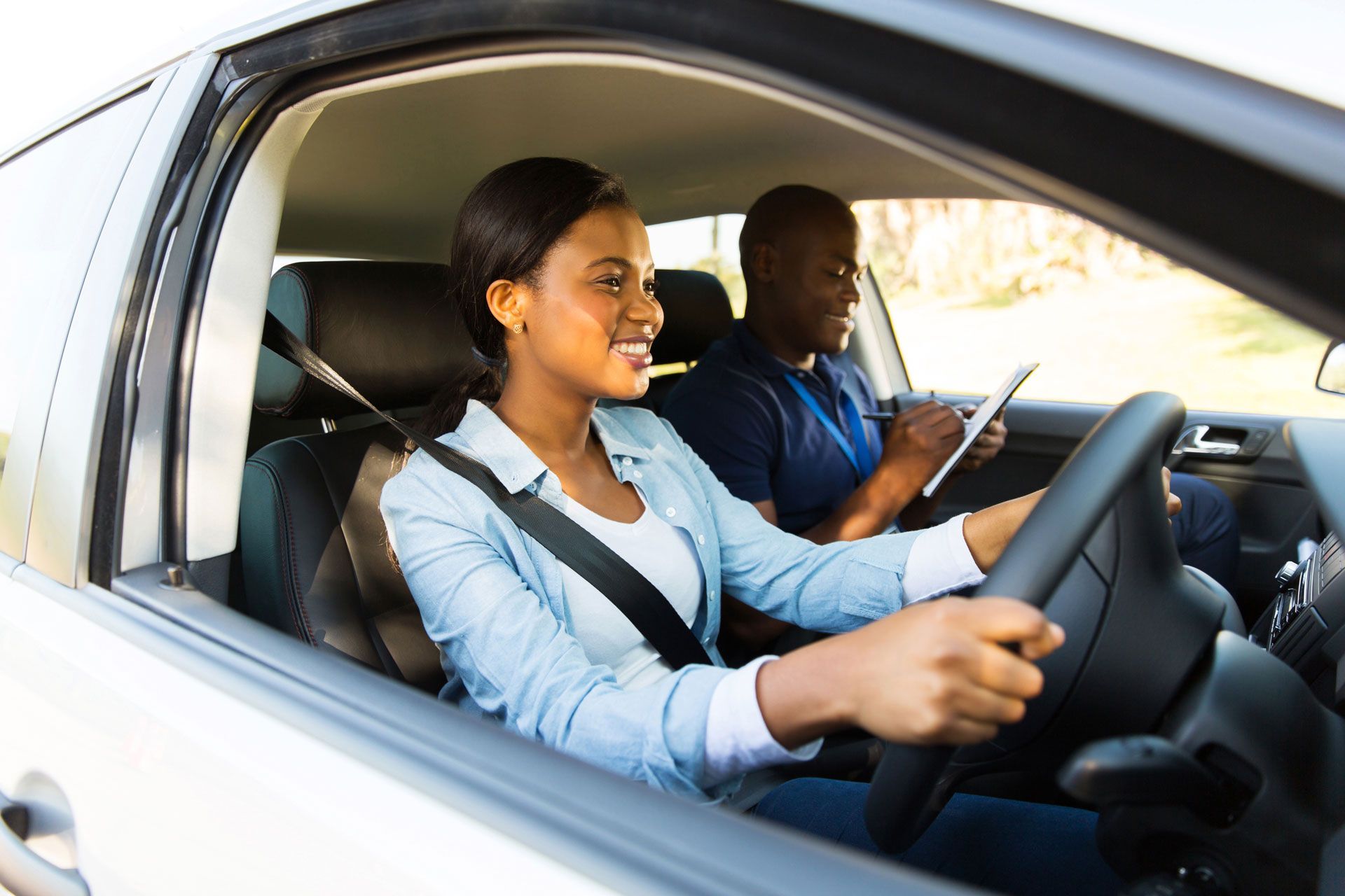 A woman is sitting in a car with a driving instructor.