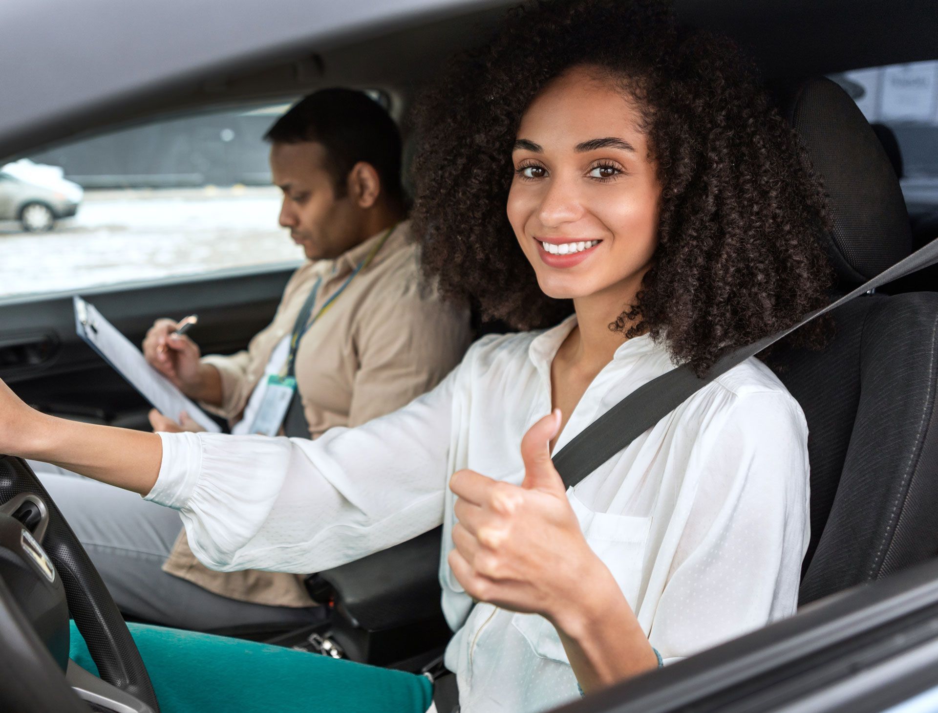 A woman is giving a thumbs up while sitting in a car.