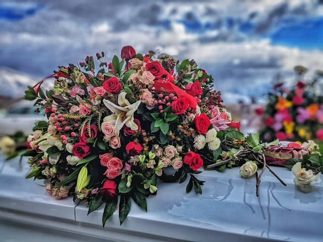 A bunch of flowers are sitting on top of a white coffin.