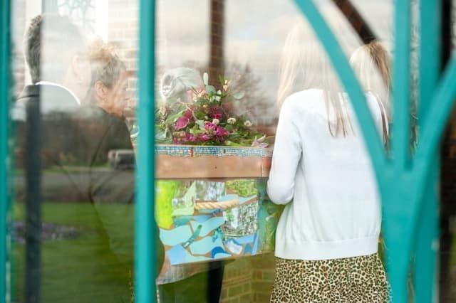 A woman is holding a box of flowers in front of a window.