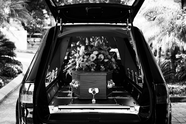 A black and white photo of a funeral car with a coffin in the back.