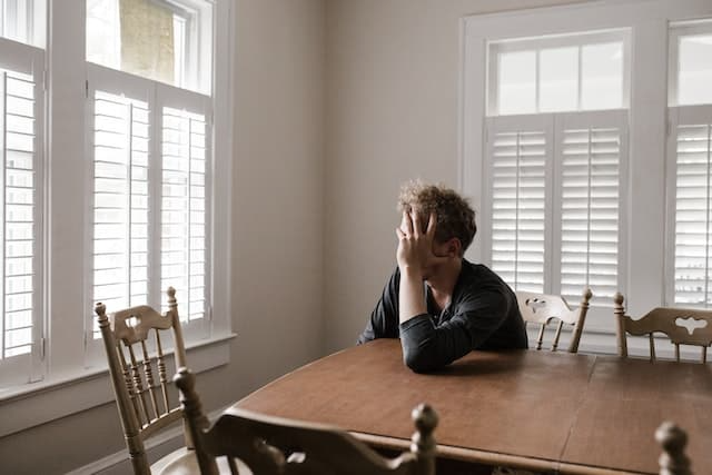 A man is sitting at a table with his head in his hands.