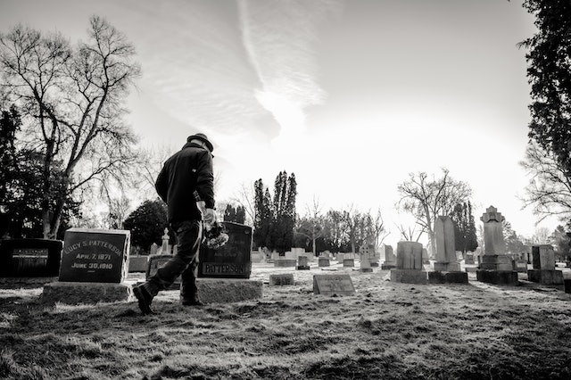 A black and white photo of a man walking through a cemetery