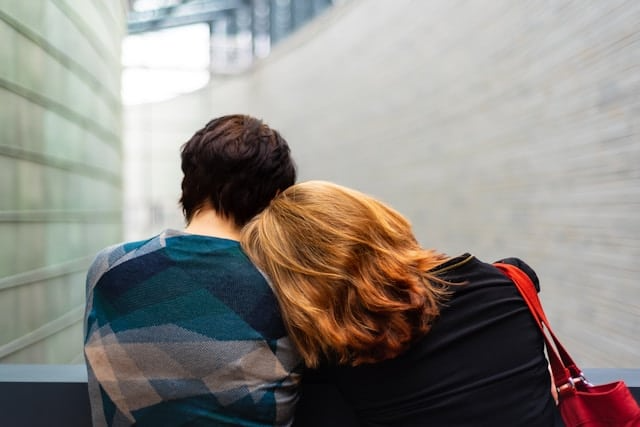 A man and a woman are sitting next to each other and hugging.