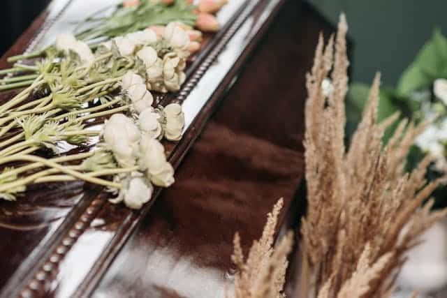 A coffin filled with flowers and grass is sitting on a table.