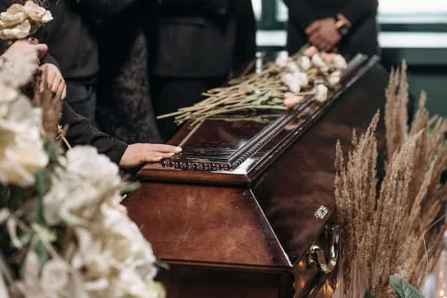 A group of people are standing around a coffin at a funeral.