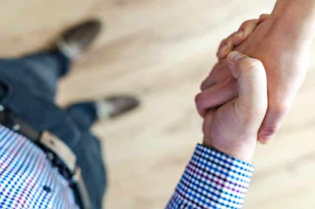 A man is shaking hands with another man on a wooden floor.