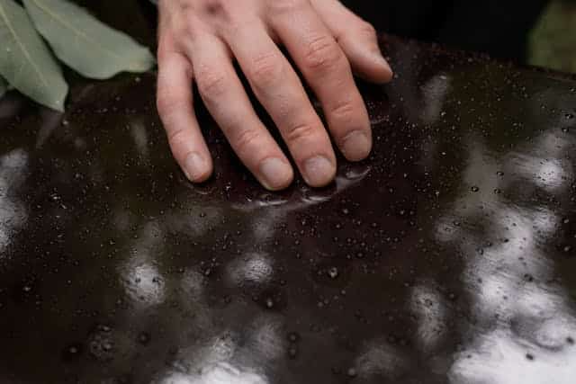 A person is touching a black surface with their hands.