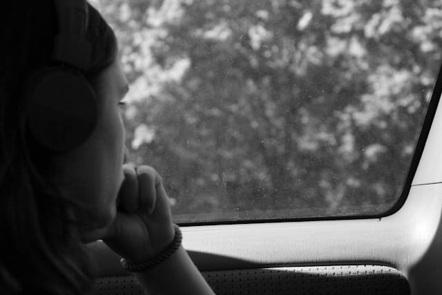 A woman is sitting in a car looking out the window.