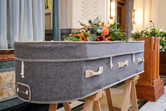 A coffin is sitting on a wooden stand in a church.