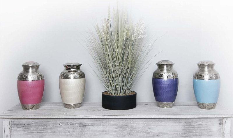 Four urns are sitting on a table next to a plant.