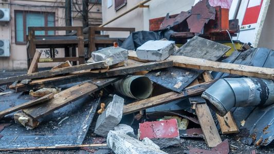 A pile of rubble is sitting on the ground in front of a building.