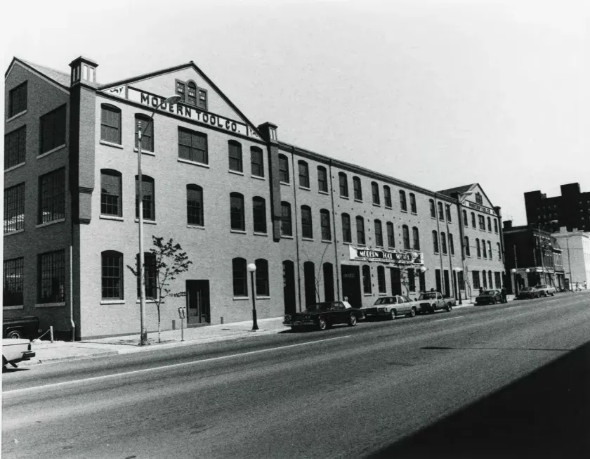 Three-story brick building with arched windows and sign reading 