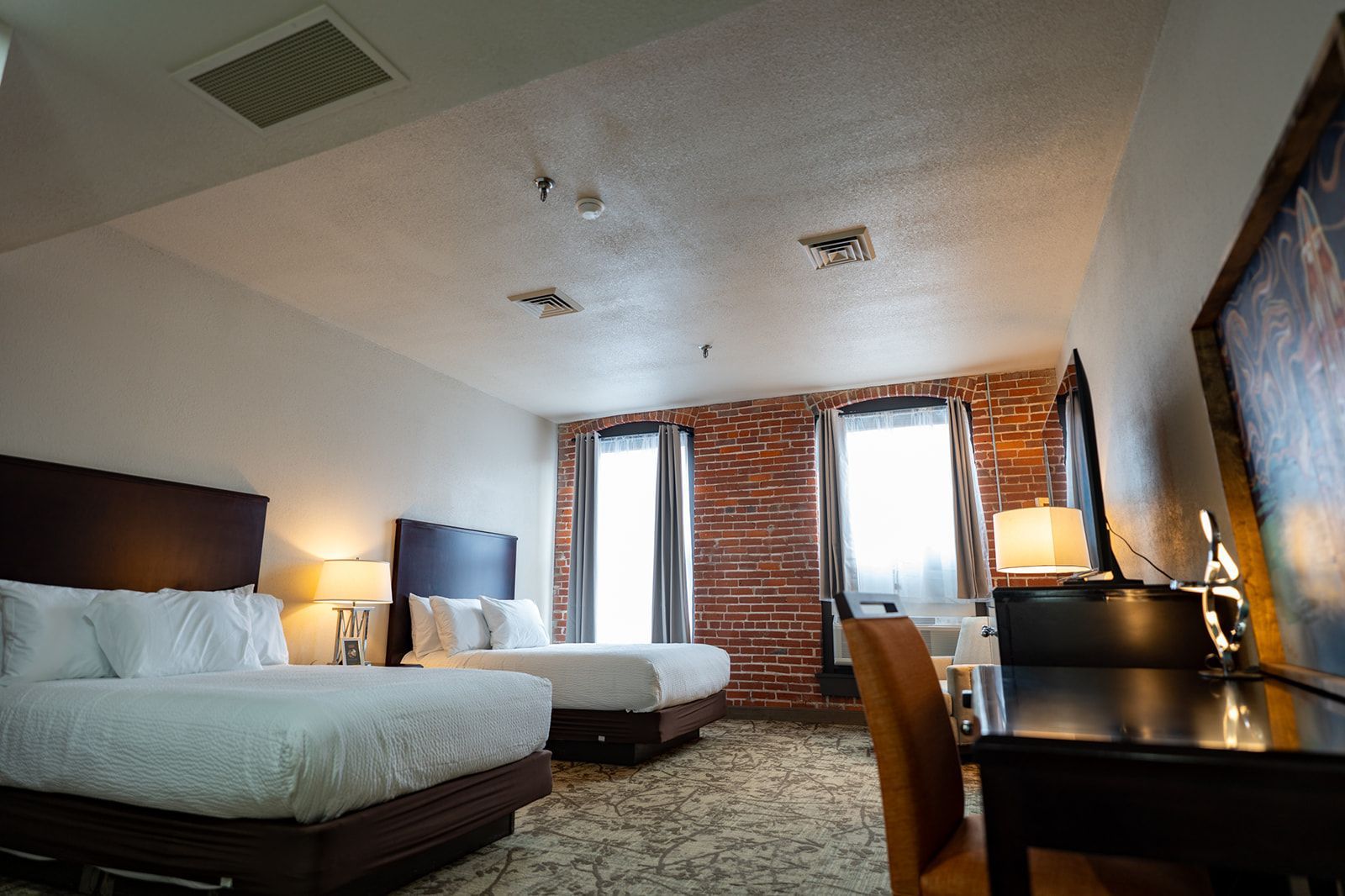 Living room with blue sofa, armchair, and ottoman. Orange pillows. Artwork on wall. Area rug.