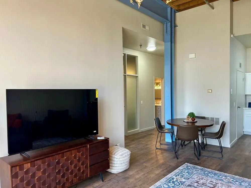 Living room with TV, dining table, and entryway to a bathroom.