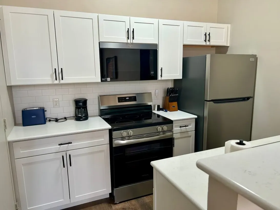 White kitchen with stainless steel appliances, cabinets, and countertops.