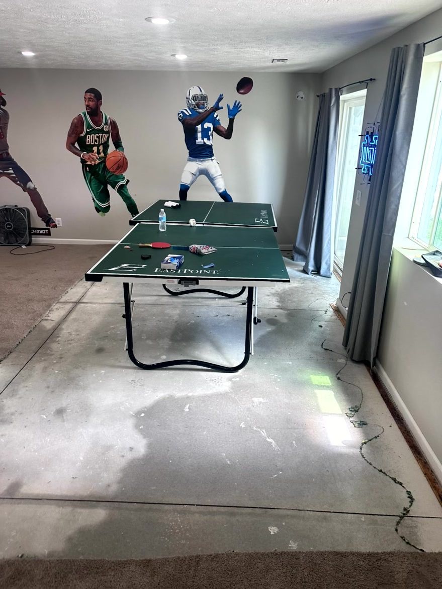 A table tennis table sits on a concrete floor drying out from water damage.